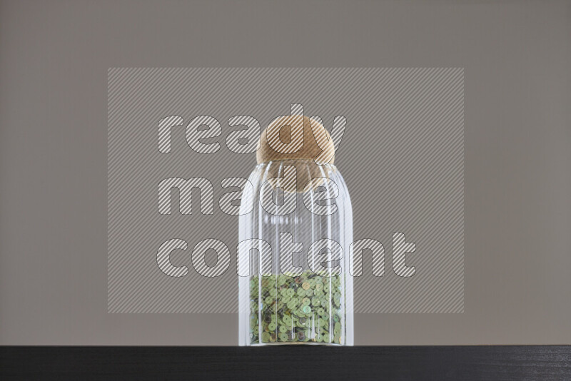 Sequins in a glass jar on black background