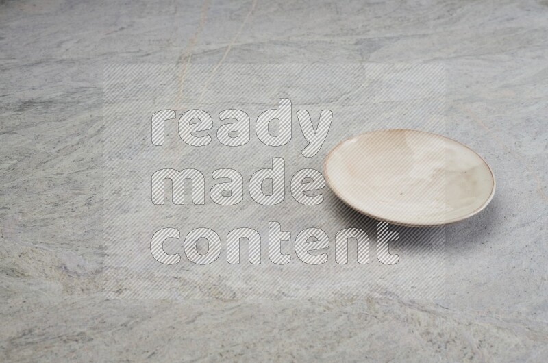 A beige pottery plate on grey marble background