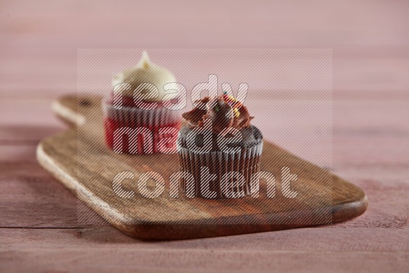 Chocolate mini cupcake topped with chocolate cream on a wooden board