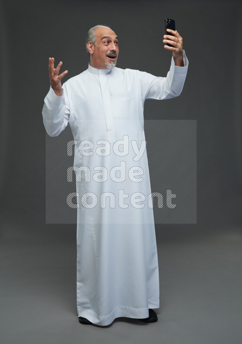 Saudi man without shomag Standing taking selfie on gray background