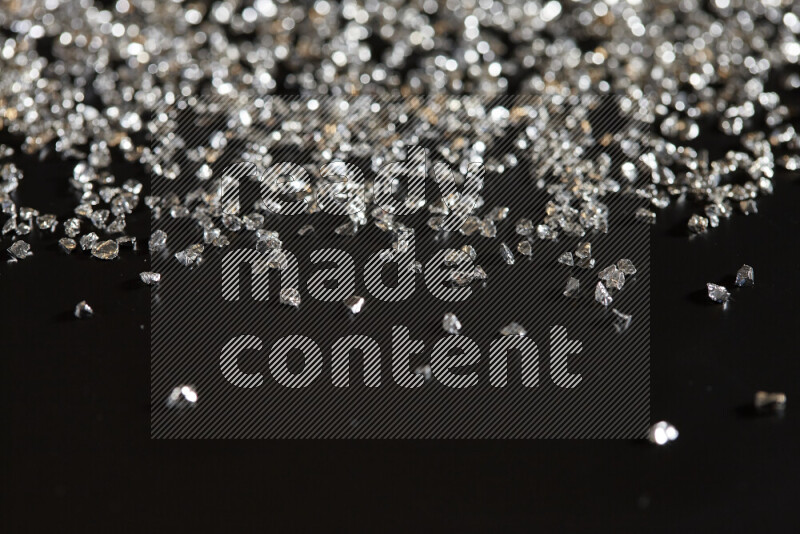 Silver shimmering fragments of glass scattered on a black background