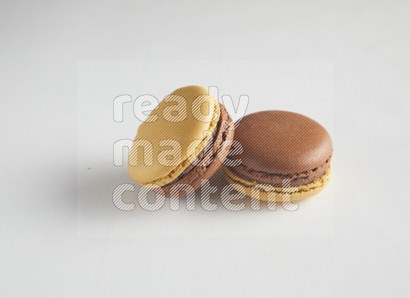 45º Shot of two Yellow and Brown Chai Latte macarons on white background