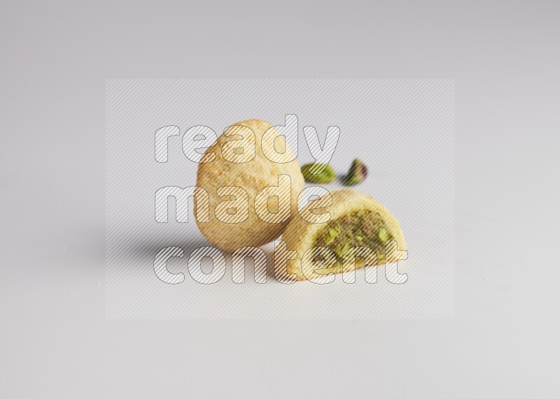 Two Pieces of Maamoul filled with pistachio paste  one of them is cut direct on white background