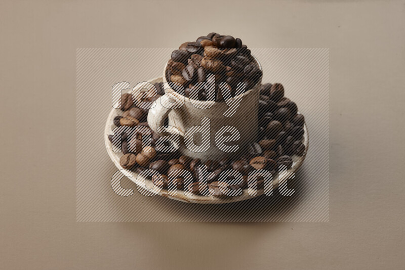 A beige pottery cup full of roasted coffee beans on beige background