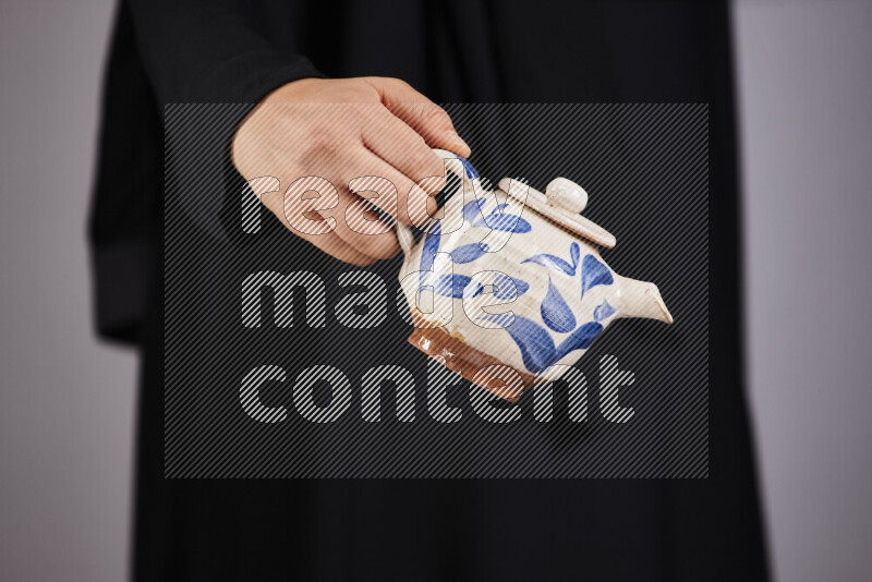 A woman in black abaya holding different pottery essentials in different positions