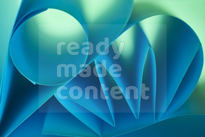 An artistic display of paper folds creating a harmonious blend of geometric shapes, highlighted by soft lighting in green and blue tones