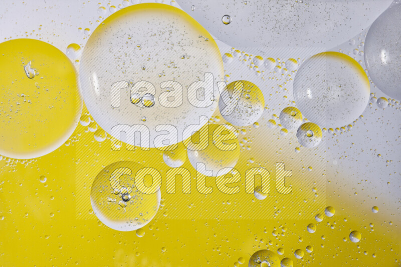 Close-ups of abstract oil bubbles on water surface in shades of white and yellow