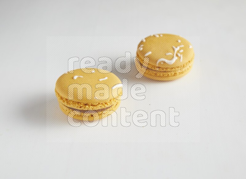 45º Shot of two Yellow Piña Colada macarons on white background