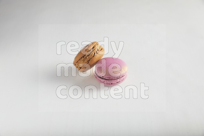 45º Shot of of two assorted Brown Irish Cream, and Purple Strawberry macarons on white background