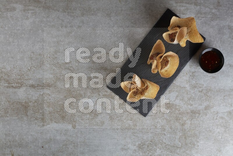 wonton cups with soy sauce ramkin on rectangle slate on grey textured counter top