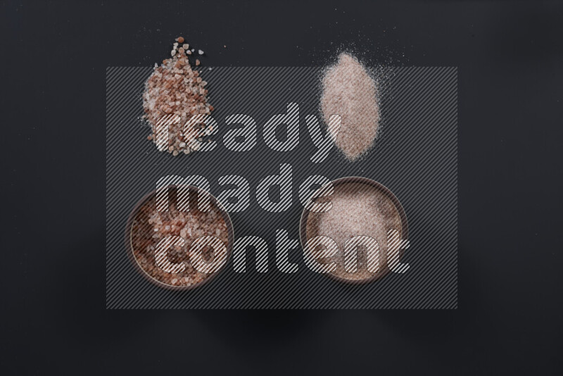 Pottery bowl full of fine himalayan salt and coarse himalayan salt on black background