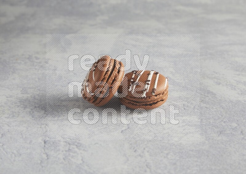 45º Shot of two Brown white marbleChocolate Caramel macarons  on white  marble background