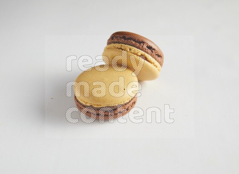 45º Shot of two Yellow and Brown Chai Latte macarons on white background