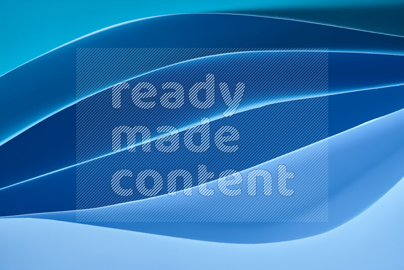 هذه الصورة تعرض تكوين فن الورق التجريدي مع منحنيات ورقية بتدرجات اللون الأزرق المكونه بواسطة الضوء الملون