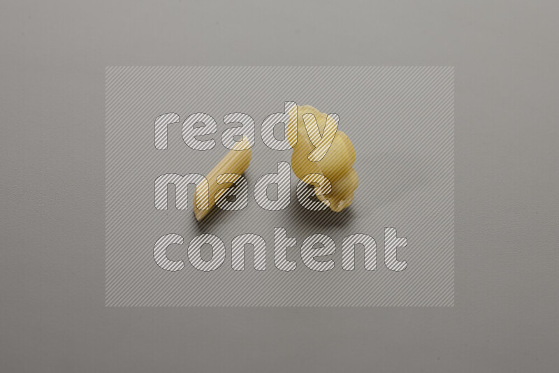 Mini penne pasta with other types of pasta on grey background