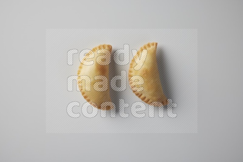 Two fried sambosa from a top angle on a white background