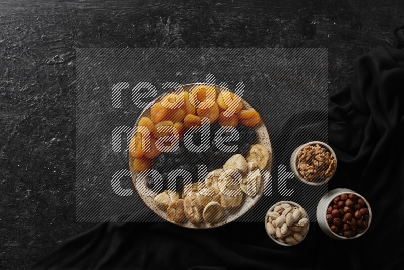 Dried fruits in a pottery bowl with nuts in a dark setup
