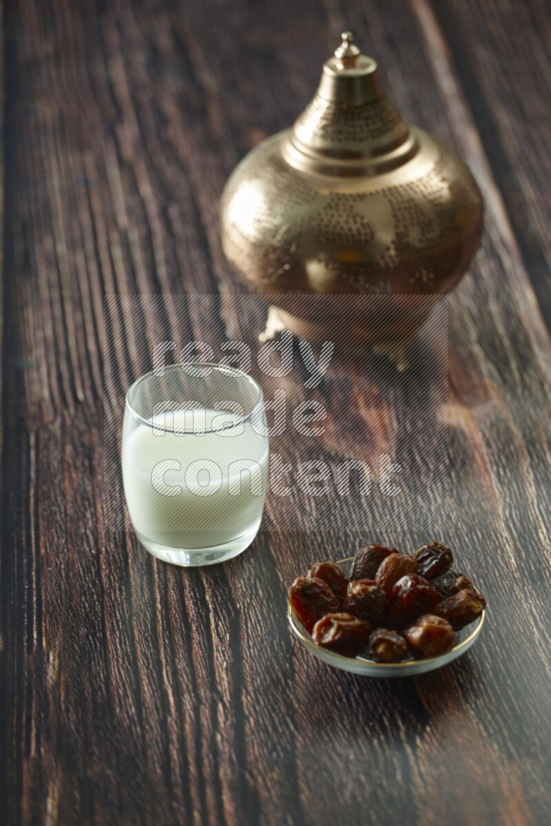 A golden lantern with different drinks, dates, nuts, prayer beads and quran on brown wooden background