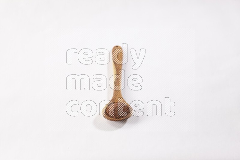 A wooden ladle full of garden cress seeds on a white flooring