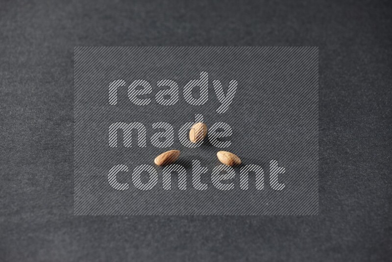 3 peeled almonds on a black background in different angles
