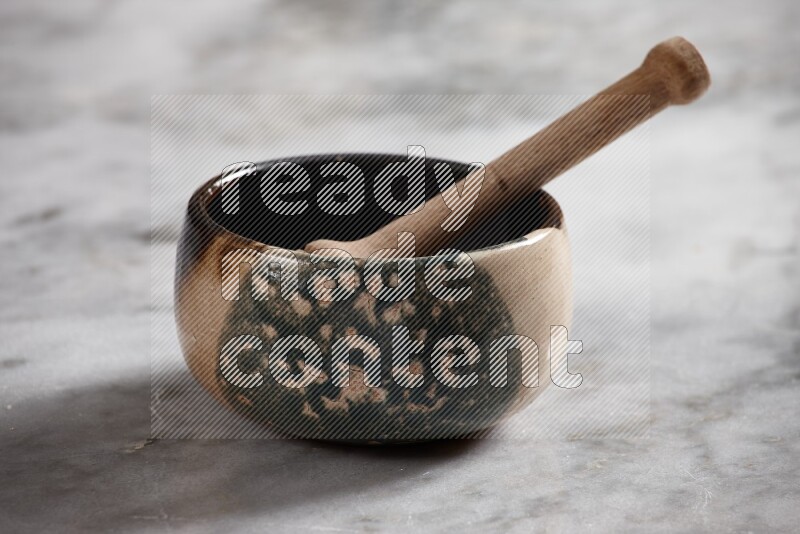 Multicolored pottery bowl with wooden honey dipper in it on grey marble background