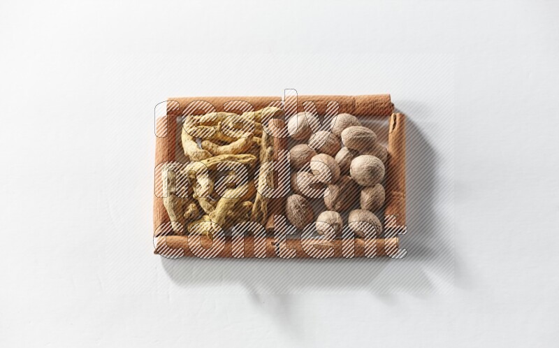 2 squares of cinnamon sticks full of turmeric fingers and nutmegs on white flooring