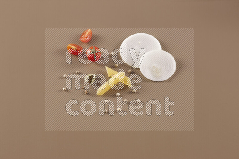 Raw pasta with different ingredients such as cherry tomatoes, garlic, onions, red chilis, black pepper, white pepper, bay laurel leaves, rosemary and cardamom on beige background