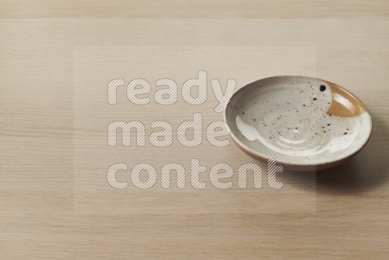 A multicolored pottery plate on light wooden background