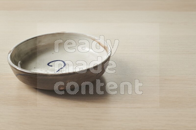 A multicolored pottery bowl on light wooden background