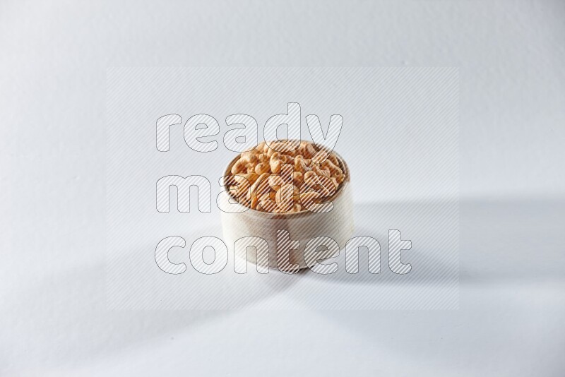 A beige ceramic bowl full of cashews on a white background in different angles