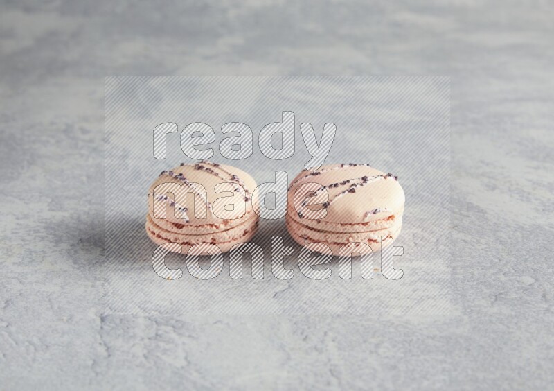 45º Shot of two pink orange blossom macarons  on white  marble background