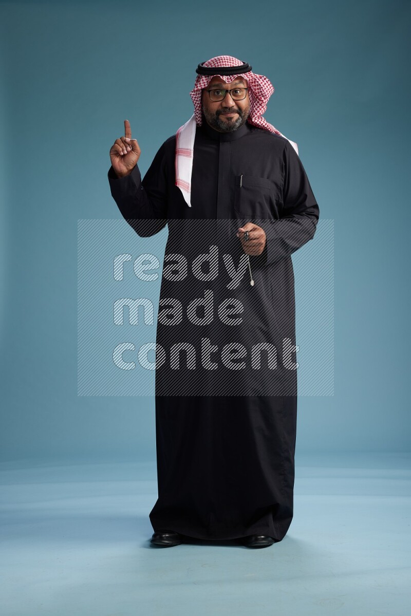 Saudi Man with shimag Standing Interacting with the camera on blue background