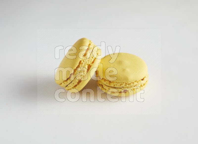 45º Shot of two Yellow Lemon macarons on white background