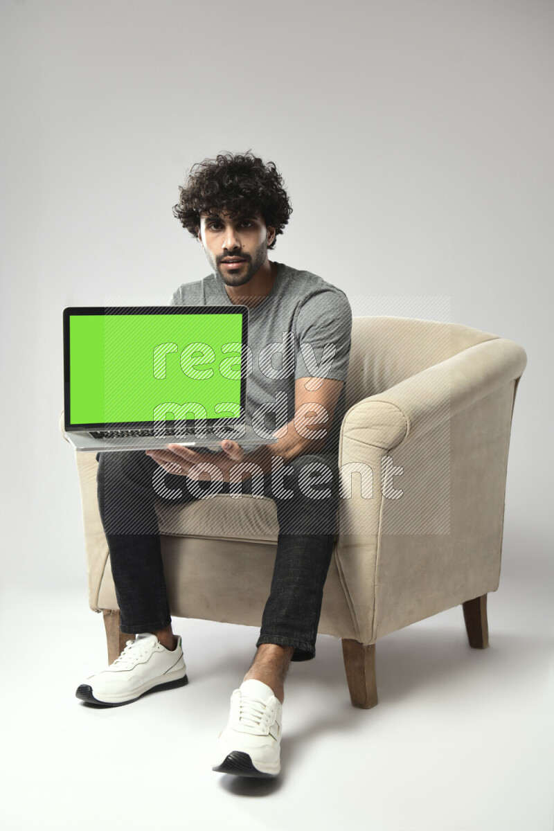 A man wearing casual sitting on a chair showing a laptop screen on white background