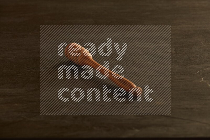 Wooden honey dipper on black slate background