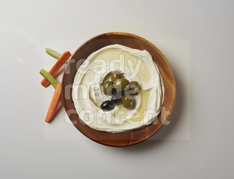 Lebnah garnished with whole olives in a wooden plate on a white background
