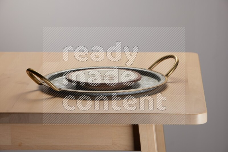 multicolored plate placed on a rounded stainless steel tray with golden handels on the edge of wooden table