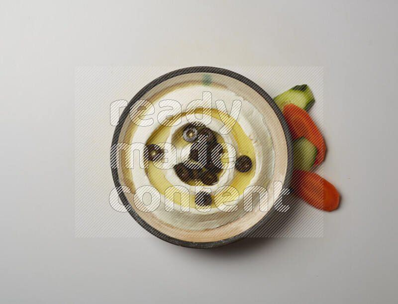 Lebnah garnished with sliced olives in a pottery plate on a white background