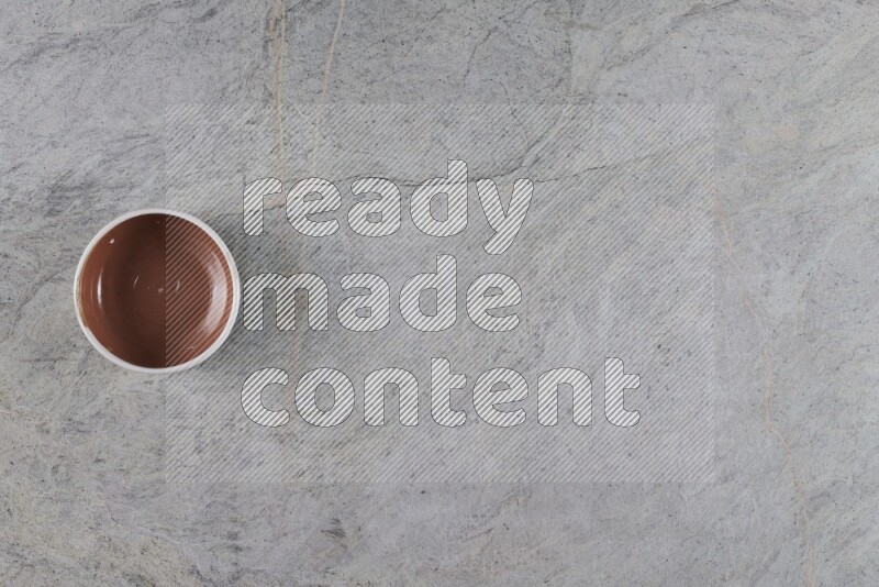 A brown pottery bowl on grey marble background
