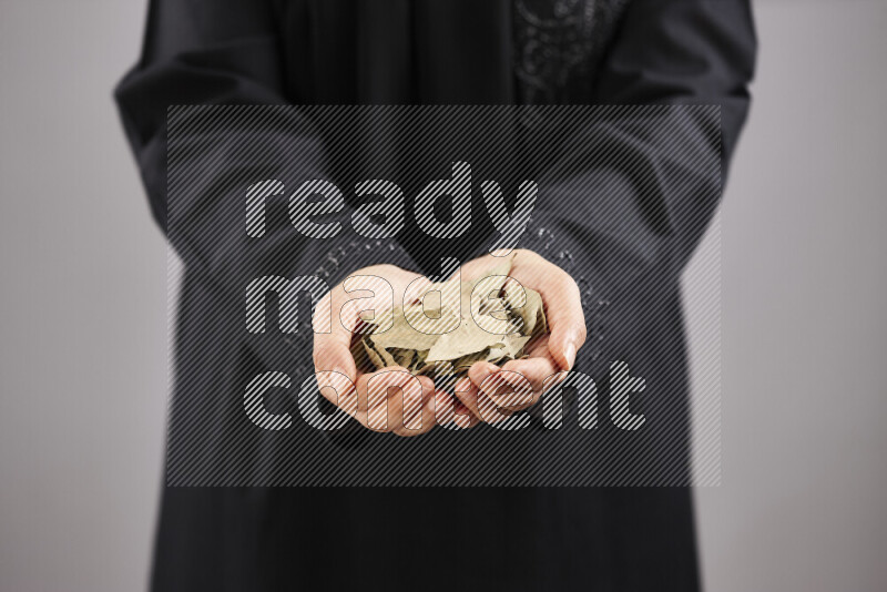 Woman in abaya holding different kinds of spices in different positions