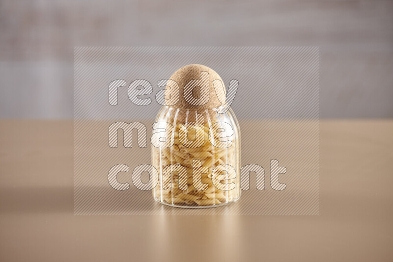 Raw pasta in glass jars on beige background