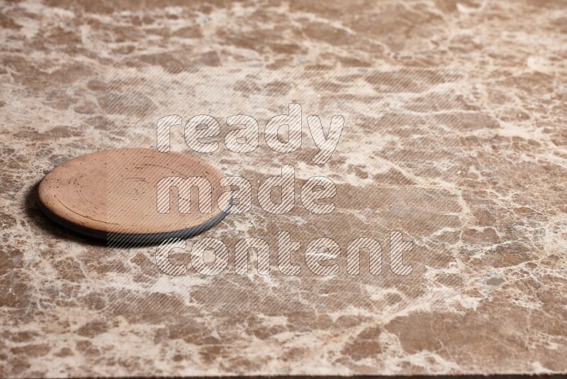 A pottery coaster on beige marble background
