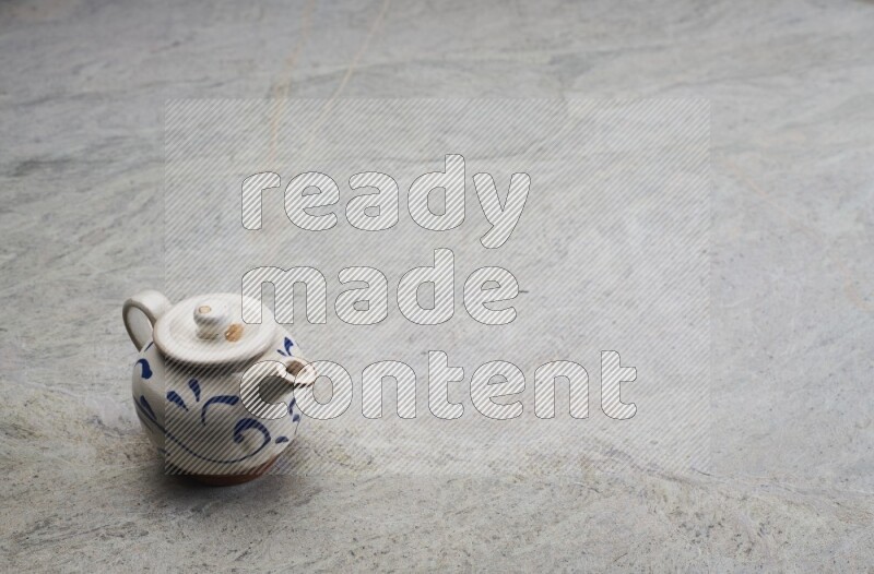 A pottery teapot on grey marble background