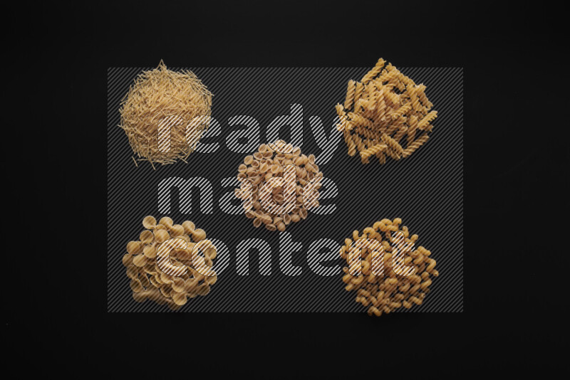 Different pasta types in bunches on black background