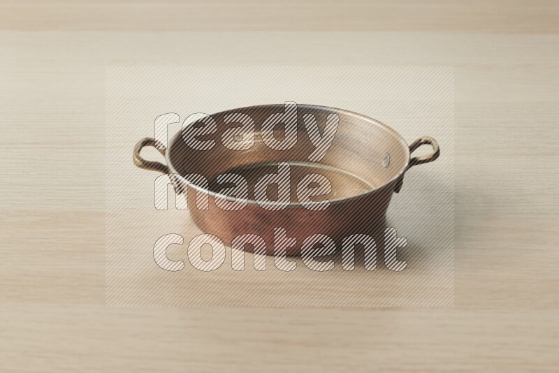 A small copper pan on light wooden background