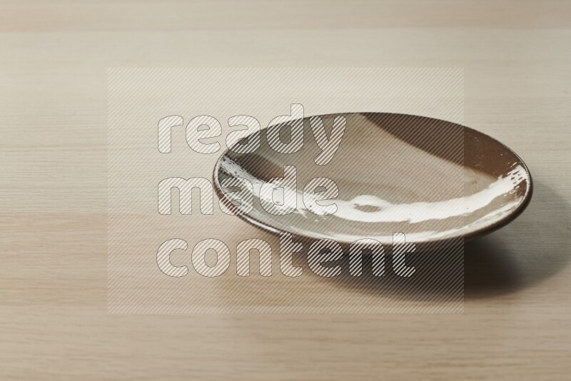 A multicolored pottery plate on light wooden background
