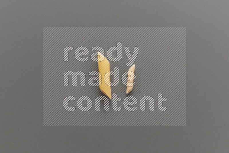 Penne pasta with other types of pasta on grey background