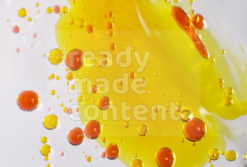 Close-ups of abstract yellow and red watercolor drops on oil Surface on white background