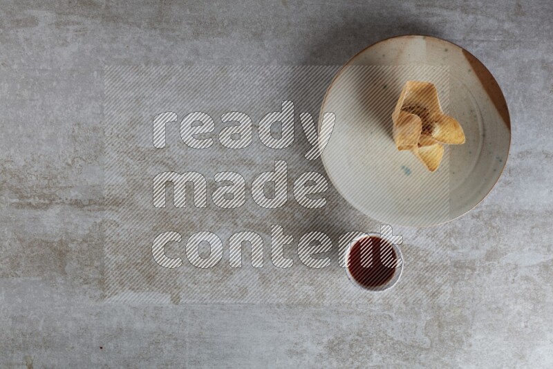 wonton cups with soy sauce ramkin on multi colored pottery on grey textured counter top
