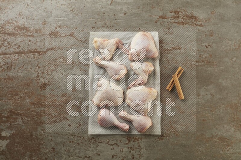 Mixed fresh chicken pieces on a parchment paper direct on a textured rustic background